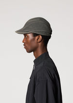 A person in a dark collared shirt is shown in profile facing left, wearing the IM MEN CARVED CAP with visible stitching and a 3D pattern, against a plain light background.