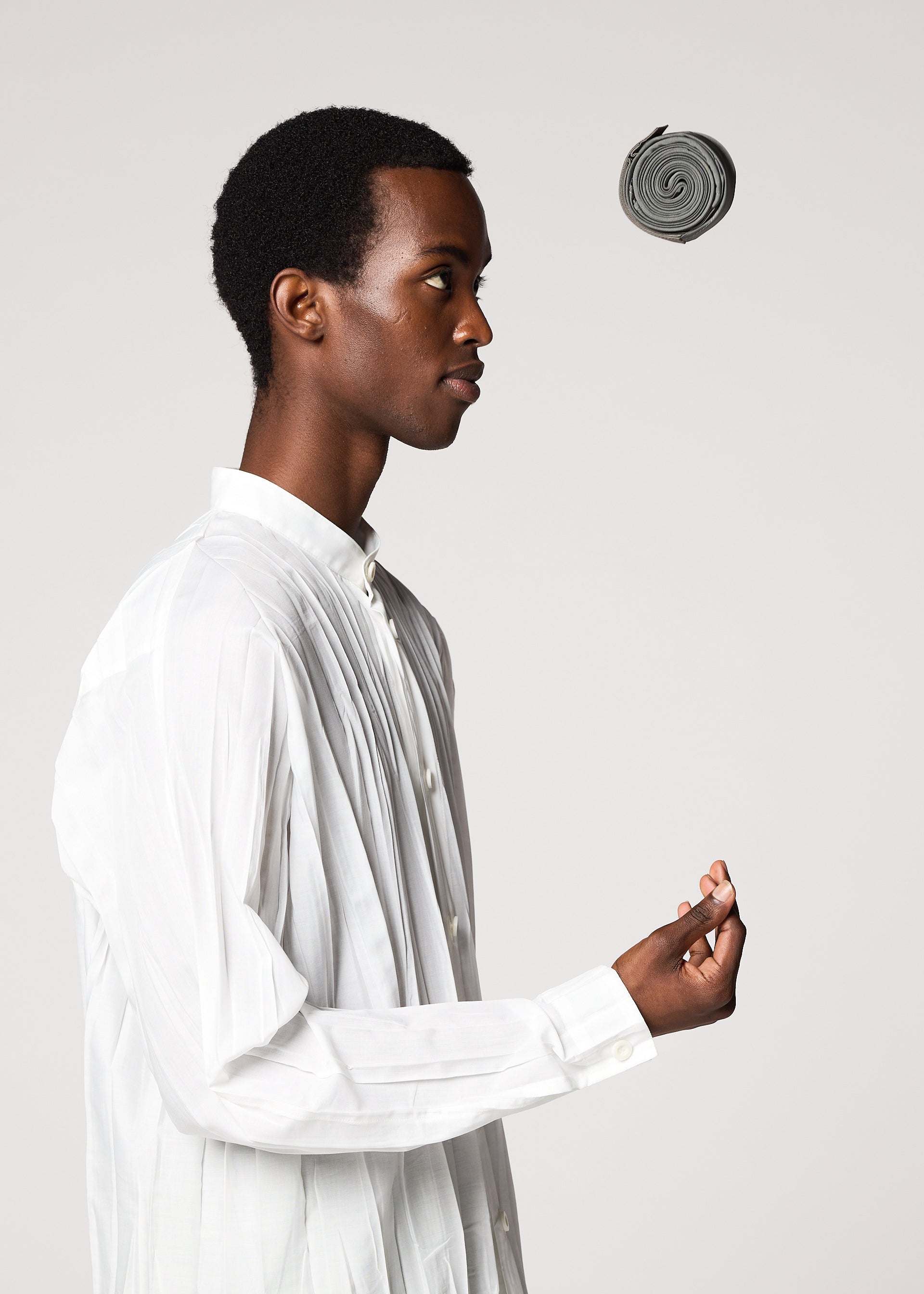 Zoomed view A person in a white button-down shirt stands in profile against a plain background, looking at the GURU GURU foldable tote bag from IM MEN as it levitates above their hand.