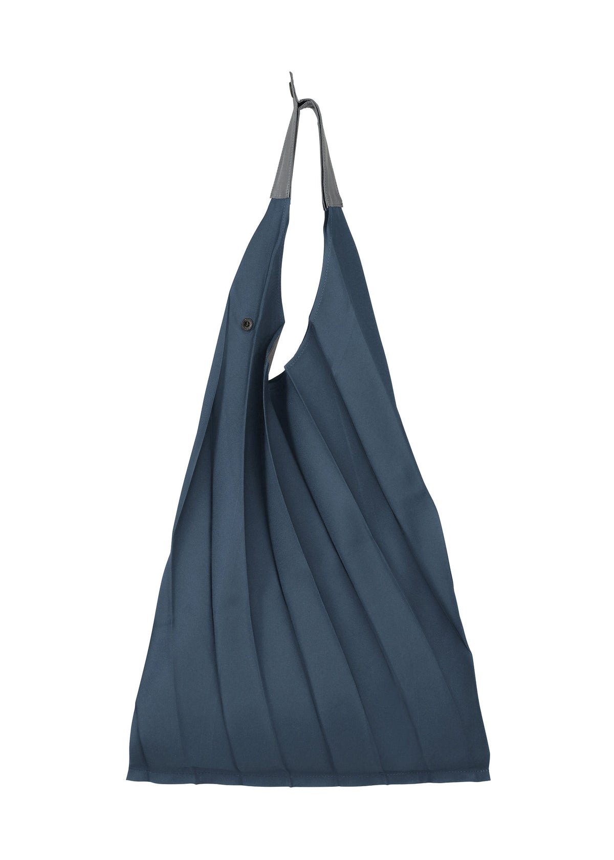 The GURU GURU tote by IM MEN is a dark blue, foldable bag featuring handmade pleats, a black button closure, gray top handles, and fits in your palm. It’s shown hanging on a hook against a white background. view 3 of 10