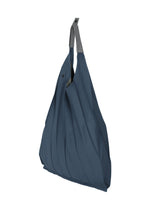 The IM MEN GURU GURU is a blue foldable tote bag with handmade pleats and gray handles, shown standing upright against a white background.