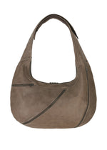 The IM MEN CARVED LEATHER BAG is a large taupe hobo made from natural leather, with a wide adjustable shoulder strap and multiple diagonal zippered pockets on the front.