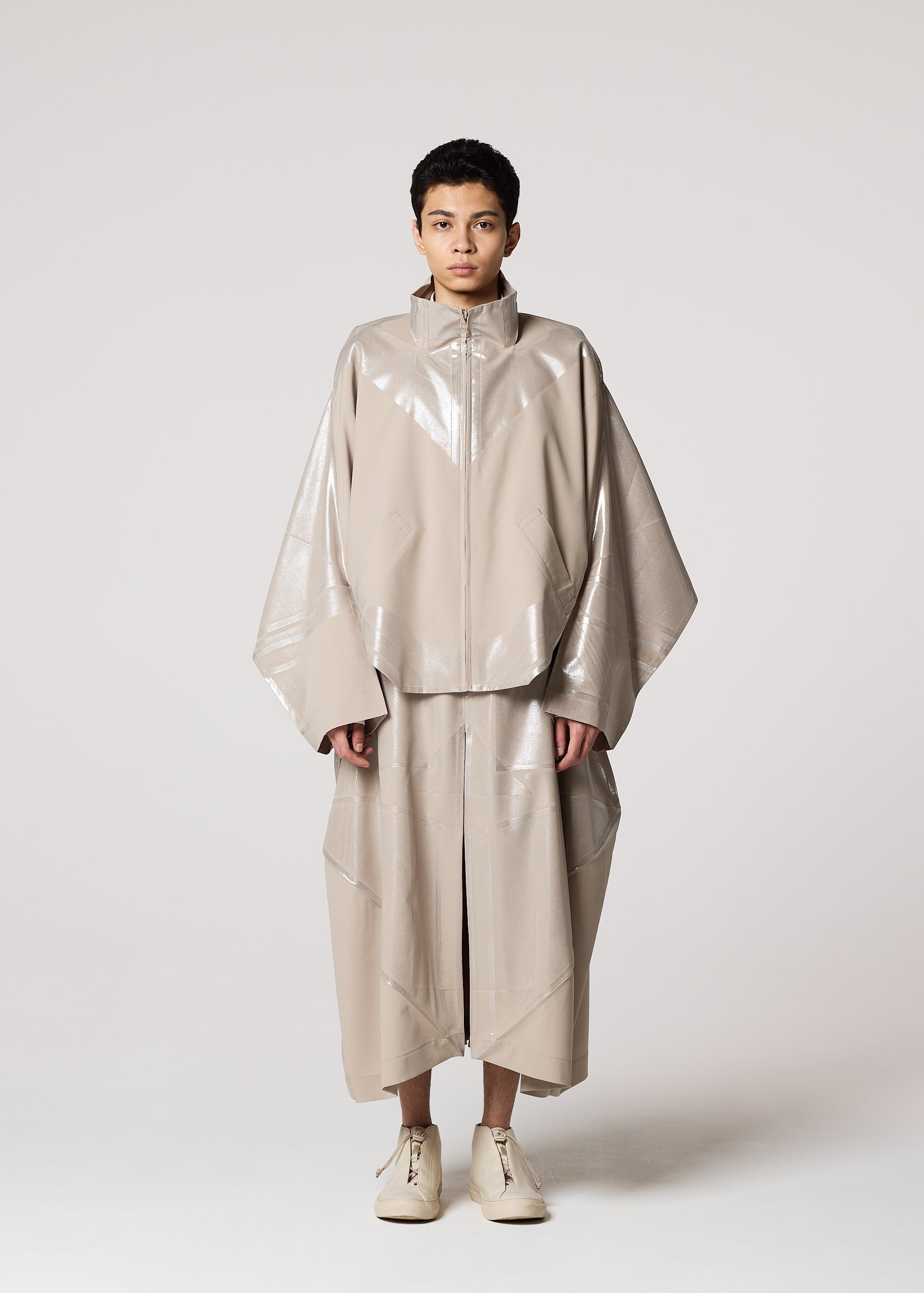Zoomed view A person faces forward in an oversized Shoji Kamoda-inspired plant-based polyester jacket with wide sleeves and loose matching shorts by IM MEN, wearing beige GINTO FLAT shoes, short hair, and a neutral expression against a light background.