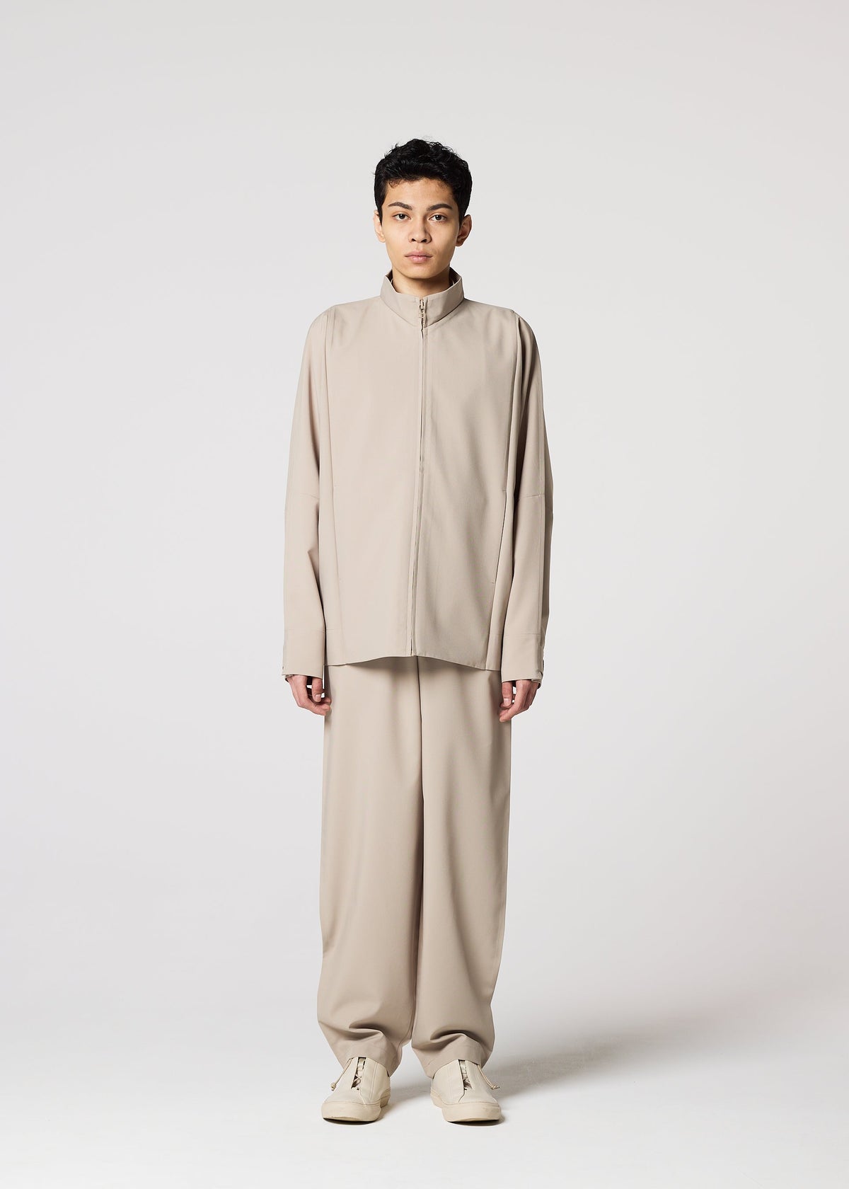A person stands facing forward, wearing the FLAT beige wrinkle-resistant jacket and matching wide-leg pants by IM MEN, paired with beige shoes, against a plain light gray background. view 10 of 13