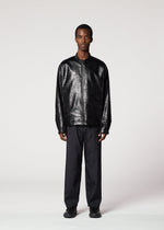 A man stands facing forward against a plain light background, wearing the GINTO silver foil jacket by IM MEN, paired with black trousers and black shoes. His hands rest by his sides, and his expression is neutral.