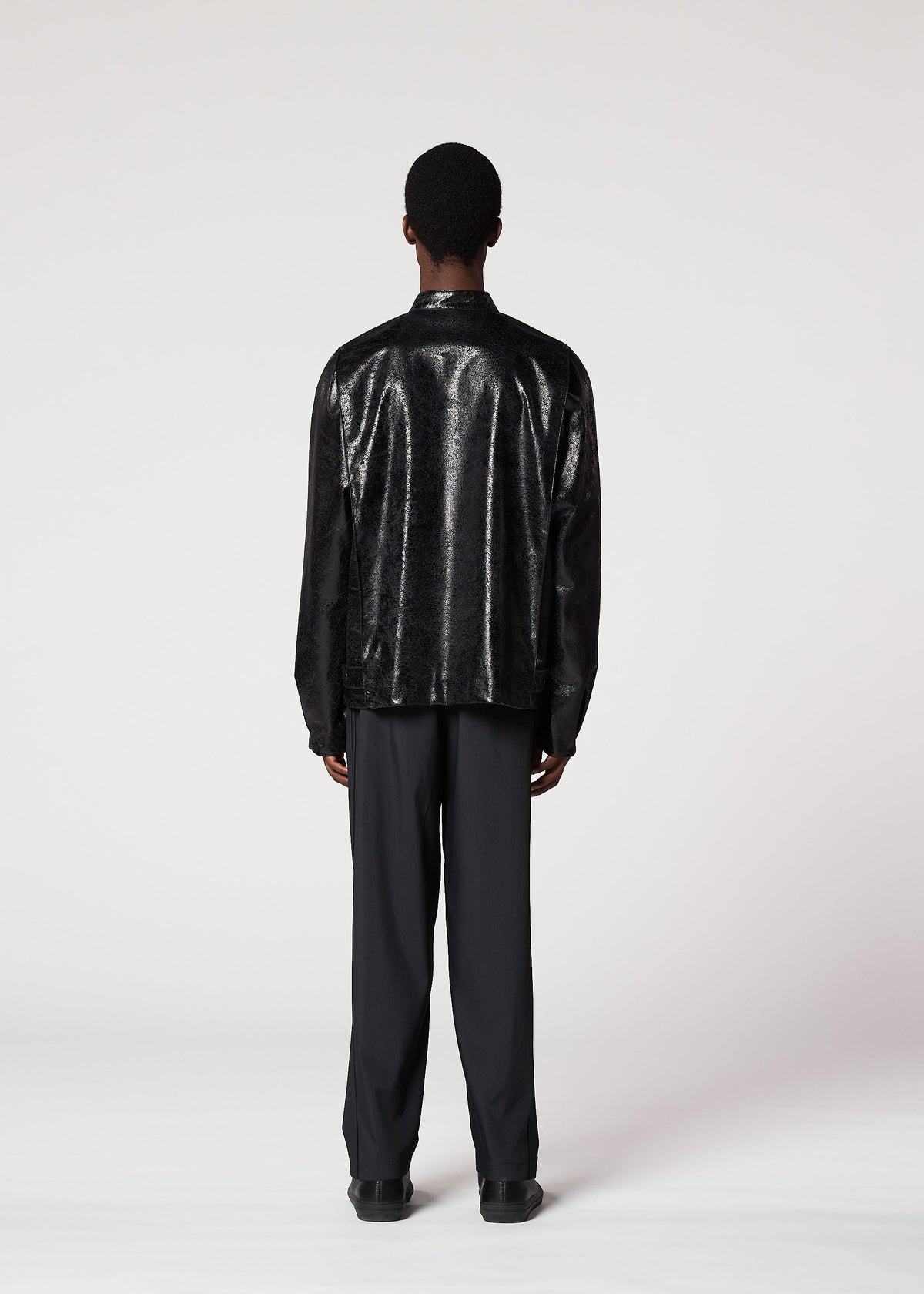 A person with short hair faces away, wearing the IM MEN GINTO silver foil jacket and black pants, inspired by Shoji Kamoda ceramics, against a plain light background. view 4 of 5