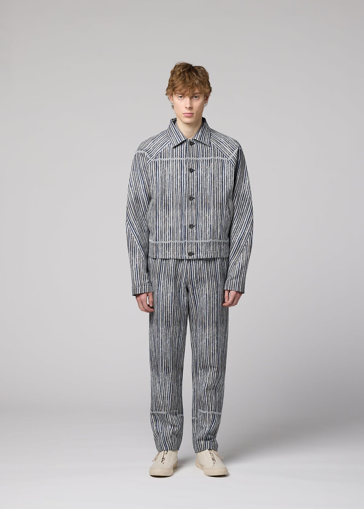 A person in the IM MEN CURVINESS set—cotton linen jacket and pants with vertical black and white stripes—stands against a light gray background in cream shoes, looking straight ahead with a neutral expression. view 5 of 8