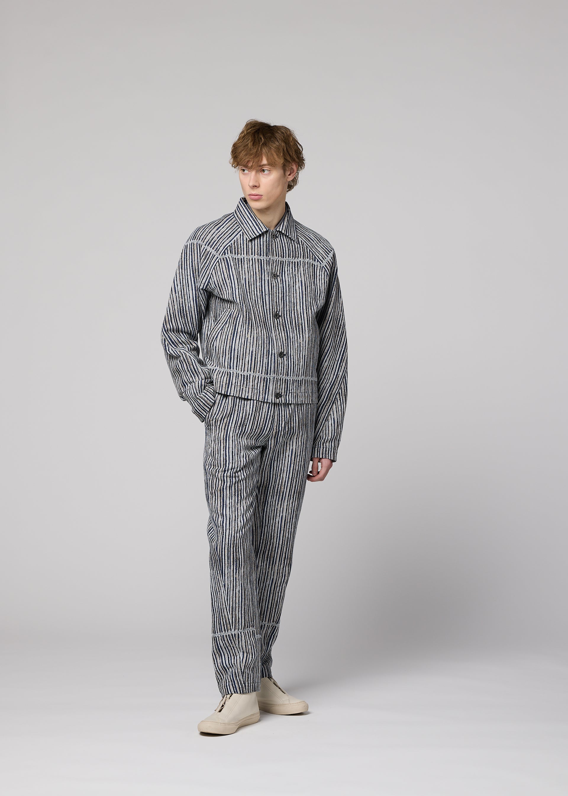 Zoomed view A person models the IM MEN CURVINESS cotton-linen textured jacket and matching pants set with cream shoes, standing against a plain light gray background, facing slightly to the side with a neutral expression.