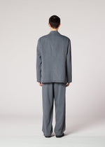 A person with short dark hair, facing away from the camera, wears IM MEN's AIR WASH lightweight gray suit jacket and matching plant-derived polyester pants against a plain light background.
