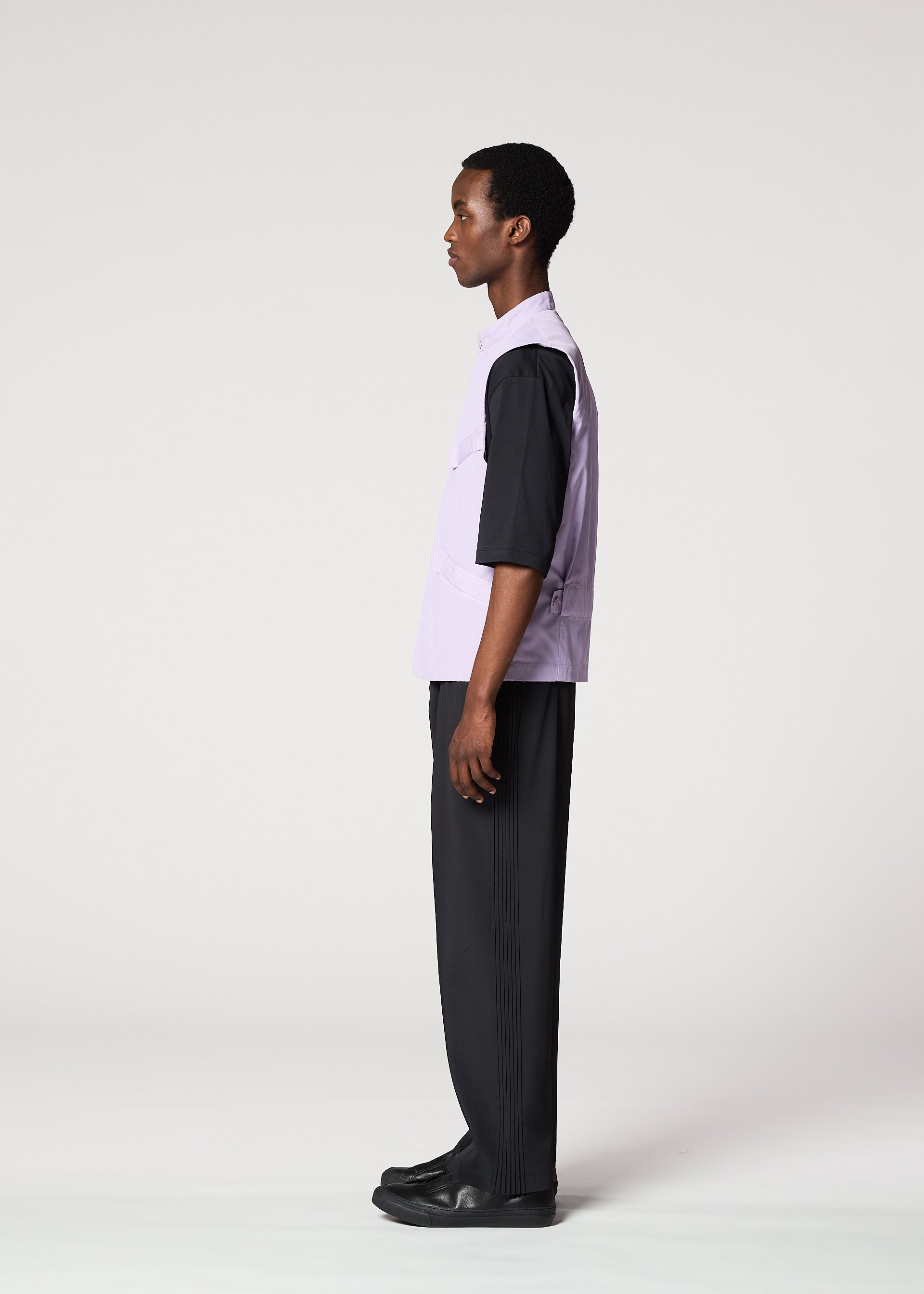 Zoomed view A person stands in profile against a plain light background, wearing the IM MEN RESILIENCE lightweight purple sleeveless vest over a black shirt, with black pants and shoes—ideal for everyday wear.