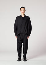 A person faces forward wearing the IM MEN SWING BLACK wrinkle-resistant suit, featuring a draped asymmetrical jacket and relaxed trousers for a loose silhouette, paired with black shoes against a plain light background.