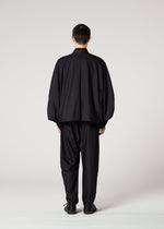 A person faces away from the camera, wearing the IM MEN SWING BLACK loose-fitting jacket and lightweight, relaxed-fit pants against a plain light background.