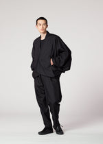 Against a plain light background, a person wears IM MEN's SWING BLACK lightweight pants with a loose silhouette, paired with a black shirt, an oversized black jacket, and black shoes. Their hands are in their pockets as they look slightly to the side.