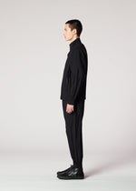 A person with short dark hair stands in profile against a plain light background, wearing IM MEN's WAFT BLACK jacket, easy care pants, and black shoes.