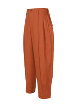 The IM MEN TOUGH LINEN pants are high-waisted, rust-colored linen trousers with a natural texture, pleated waist, side pockets, and wide legs, shown against a white background.