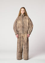A person with long curly hair wears the IM MEN ELEMENTS loose-fitting brown textured jacket and matching wide pants, crafted from thick cotton, standing against a plain light gray background.