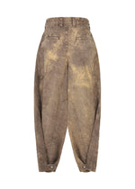 The ELEMENTS pants by IM MEN are brown, high-waisted, loose-fit wide pants in thick cotton with a distressed washed effect, visible stitching, angled seams, side pockets, buttoned cuffs, and a sculptural design.