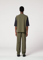 A person faces away from the camera wearing the IM MEN KAIYU suit—olive green sleeveless vest, ash glaze pants, and a short-sleeved black shirt—set against a plain light background.
