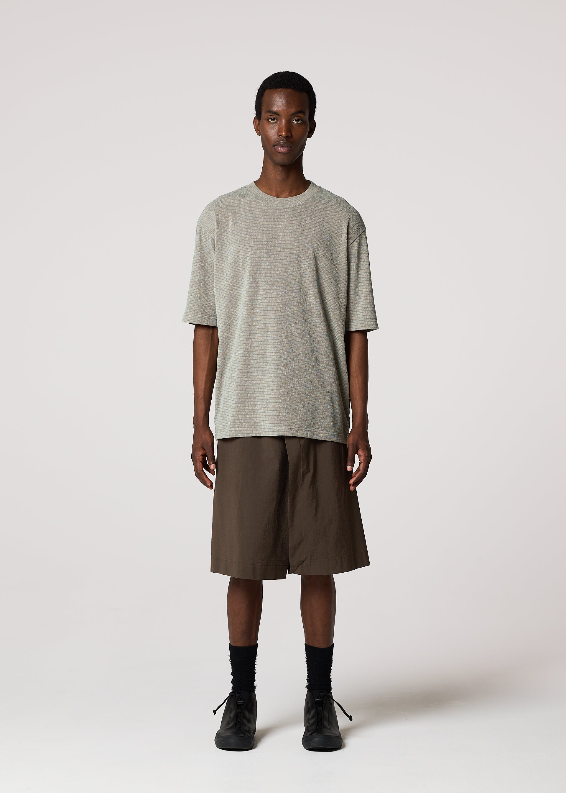 Zoomed view A person faces forward, wearing IM MEN’s NAVY BOTTOMS with a loose light gray t-shirt, black socks, and black shoes against a plain light background.