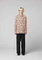 A person with blond, tousled hair faces forward, wearing the IM MEN VASE JACQUARD SHIRT with a dark abstract pattern and black wide-leg pants, set against a plain light gray background.