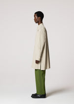 A person stands in profile wearing the IM MEN WHITE SHIRT with green pleated pants and black shoes against a plain light background—an understated look ideal for formal occasions.