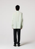 A person faces away from the camera, wearing IM MEN's STRIPE LINEN SHRINK shirt with black pants against a plain light background.