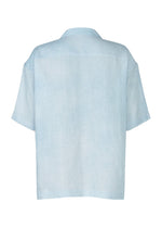 Back view of the FLOATING LINEN shirt by IM MEN in light blue. This short-sleeved, collared design offers a loose, boxy fit made from lightweight linen-like fabric for an effortlessly airy, minimal look without visible buttons or patterns.