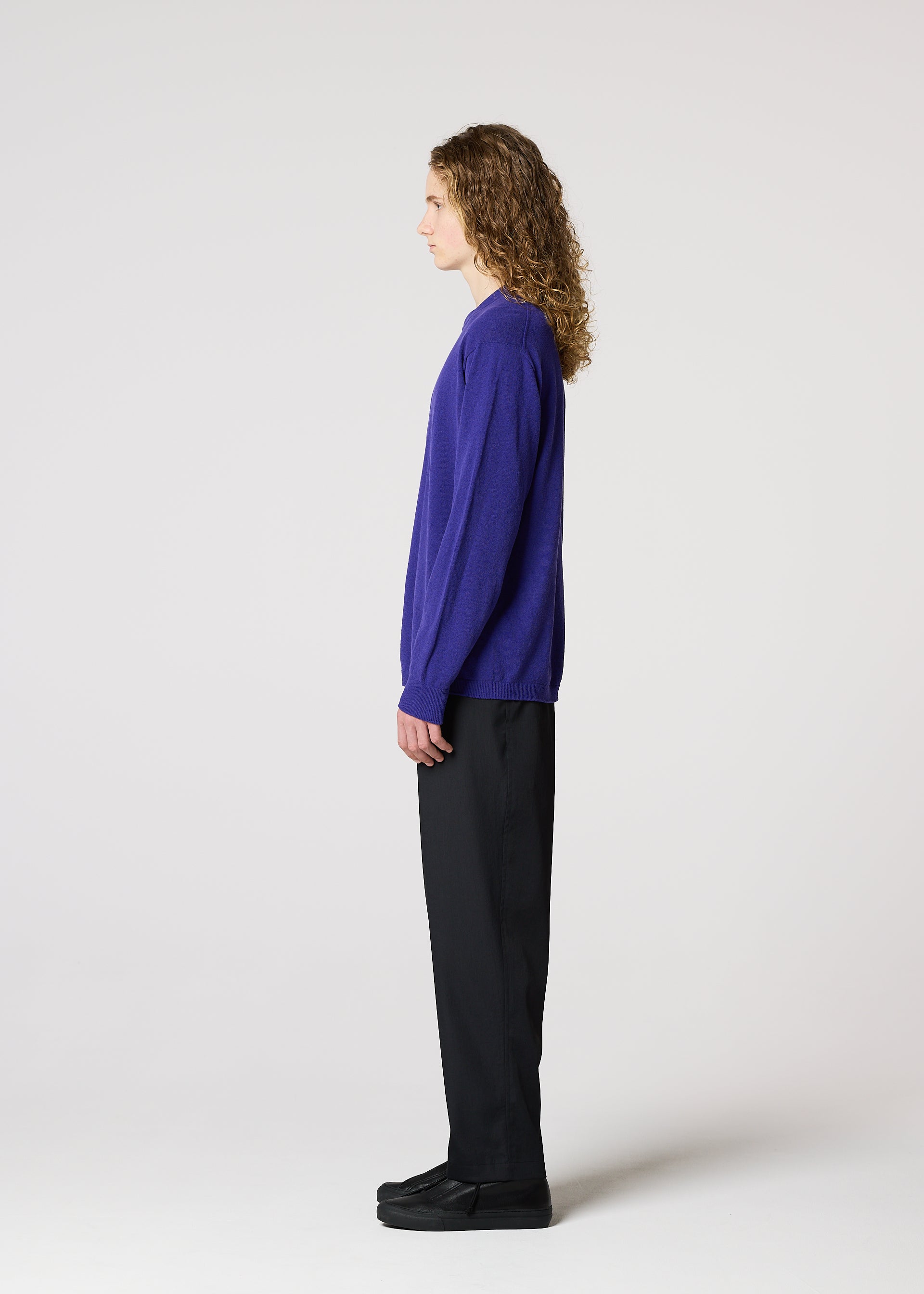 Zoomed view A person with long curly hair wears the IM MEN COMFORT purple long-sleeved knit top, made from breathable cotton nylon yarn, along with black pants and black shoes, standing in profile against a plain white background.