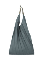 The GURU GURU by IM MEN is a teal-blue, triangular foldable tote bag with handmade pleats, a single button closure, and two beige handles joined at the top by a metal hook. - BLUE GRAY （no.16）