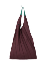 The GURU GURU by IM MEN is a maroon foldable tote with green handles, handmade pleats, an S-shaped curve for a sculptural look, and a top button closure. - BORDEAUX （no.84）
