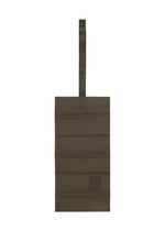 A rectangular olive-green polyester suede bag with horizontal stitching, a snap-button top strap, and a small square IM MEN PATA PA patch on the bottom right.