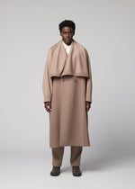 A person stands facing forward against a plain gray background, wearing the IM MEN FRONT BACK long light brown wool coat with wide lapels from the Autumn Winter Collection, paired with matching pants featuring a subtle satin back and dark shoes.