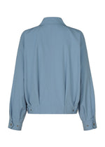 The COMFORT COTTON jacket by IM MEN is crafted from high-twist organic cotton in light blue. Designed with long sleeves, this jacket is shown from the back, showcasing its crisp, smooth texture. It features a collar, buttoned cuffs, and adjustable waist tabs secured with metal snaps for a refined finish.