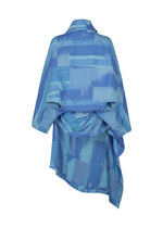The IM MEN KASURI shirt is an asymmetrical blue piece inspired by traditional Kasuri weaving, showcasing abstract geometric patterns, a draped fabric detail at the back, and a loose, oversized fit.