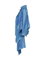 The KASURI jacket by IM MEN is crafted in a kimono-inspired silhouette with a high collar and loose, flowing sleeves. Showcased in blue patterns, this elegant drape jacket highlights the distinctive texture of the traditional Kasuri weaving technique and is photographed in side profile against a white background.