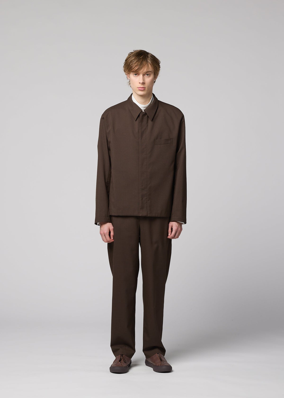 A person with short light brown hair faces forward, wearing the IM MEN SUAVE wool blend jacket and matching brown trousers with brown shoes, against a plain light gray background. view 6 of 9