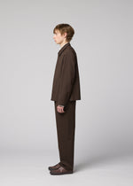 A person with short hair stands in profile against a plain background, wearing the IM MEN SUAVE loose-fitting wool blend jacket and matching pants, paired with brown shoes.