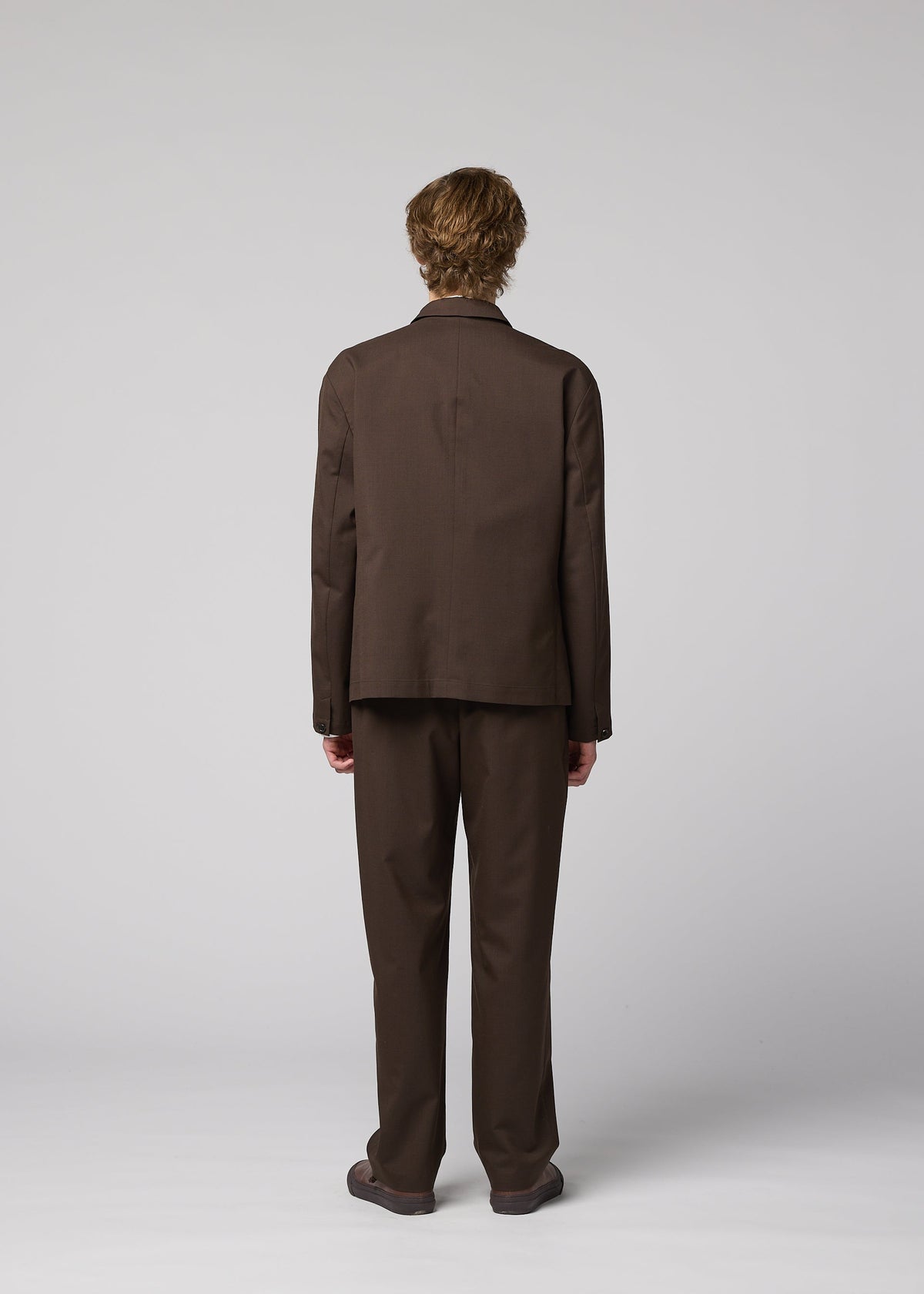A person with short, light brown hair is seen from behind in a loose-fitting IM MEN SUAVE wool blend jacket and brown shoes, creating a sleek silhouette against a plain light gray background. view 8 of 9