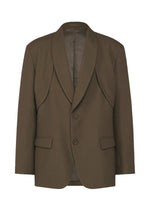 The IM MEN SHRINK WOOL is a brown crepe-like jacket with two buttons, notched lapels, flap pockets, and a curved front seam detail from the Autumn Winter 2026/27 collection, shown on a white background.