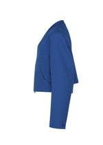 Side view of the IM MEN SHRINK WOOL jacket in cobalt blue, featuring long sleeves, a collarless design, crepe-look texture, and a structured fit in hard-twist wool, shown on a plain white background.