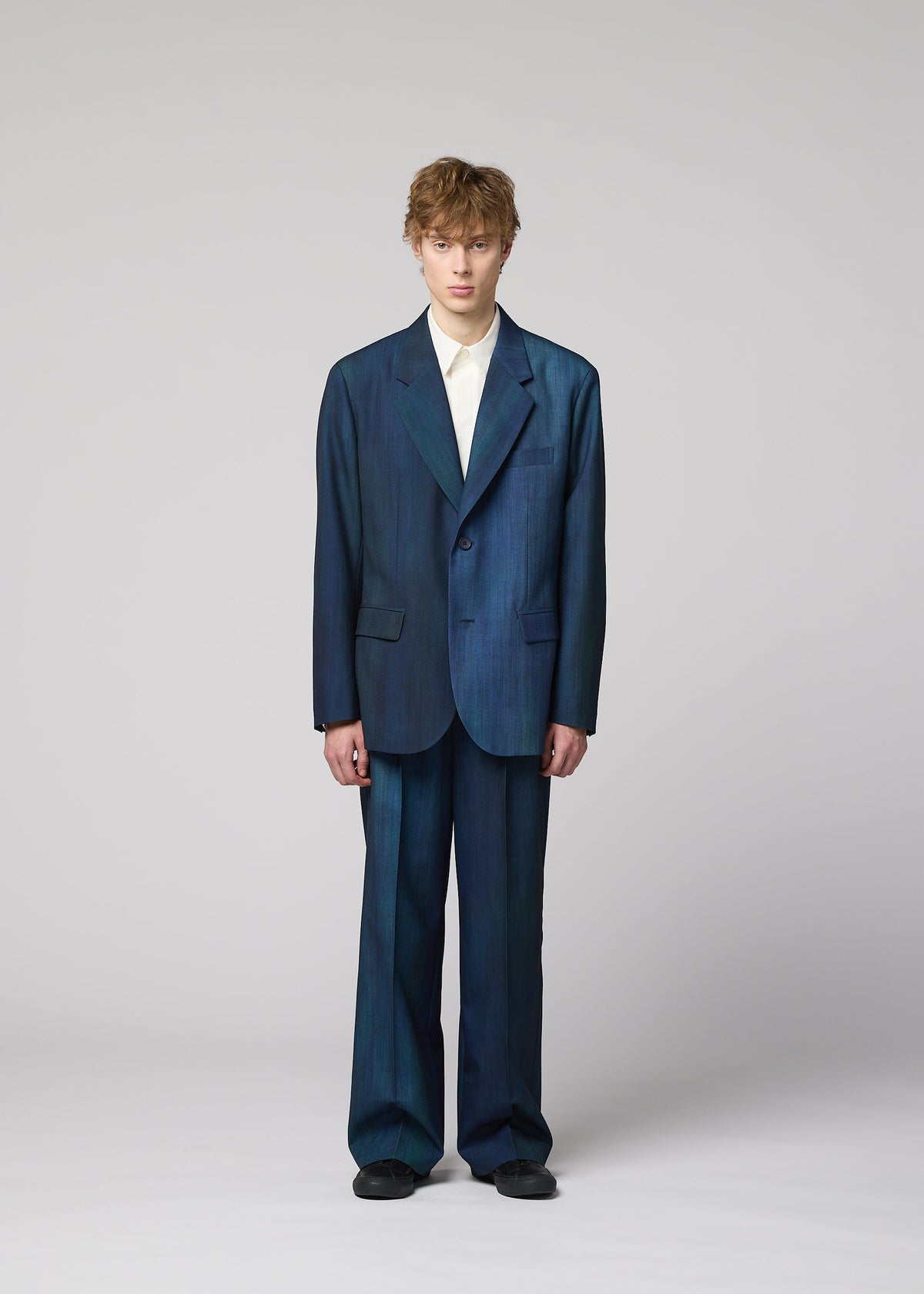 Zoomed view A person with short, wavy hair stands against a plain background, wearing an oversized IM MEN GRADATION WOOL jacket and wide pants, a white collared shirt, and black shoes.