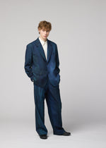 A person with light brown hair wears the oversized, dark blue GRADATION WOOL jacket by IM MEN, hands in pockets, looking at the camera.