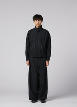 A person stands facing forward against a light gray background, wearing IM MEN's WAFT BLACK: a loose-fitting, linen-textured jacket with matching wide pants and black shoes. The adjustable hem and neutral expression complete the refined minimalist look.