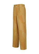 Discover the KASURI pants by IM MEN: wide-leg trousers in a light brown and beige patchwork motif, highlighted with a button closure and pleated front. Expertly crafted to showcase the artistry of traditional Kasuri weaving, these pants add rich texture and refined artisanal detail. Presented at a slight angle against a clean white background.