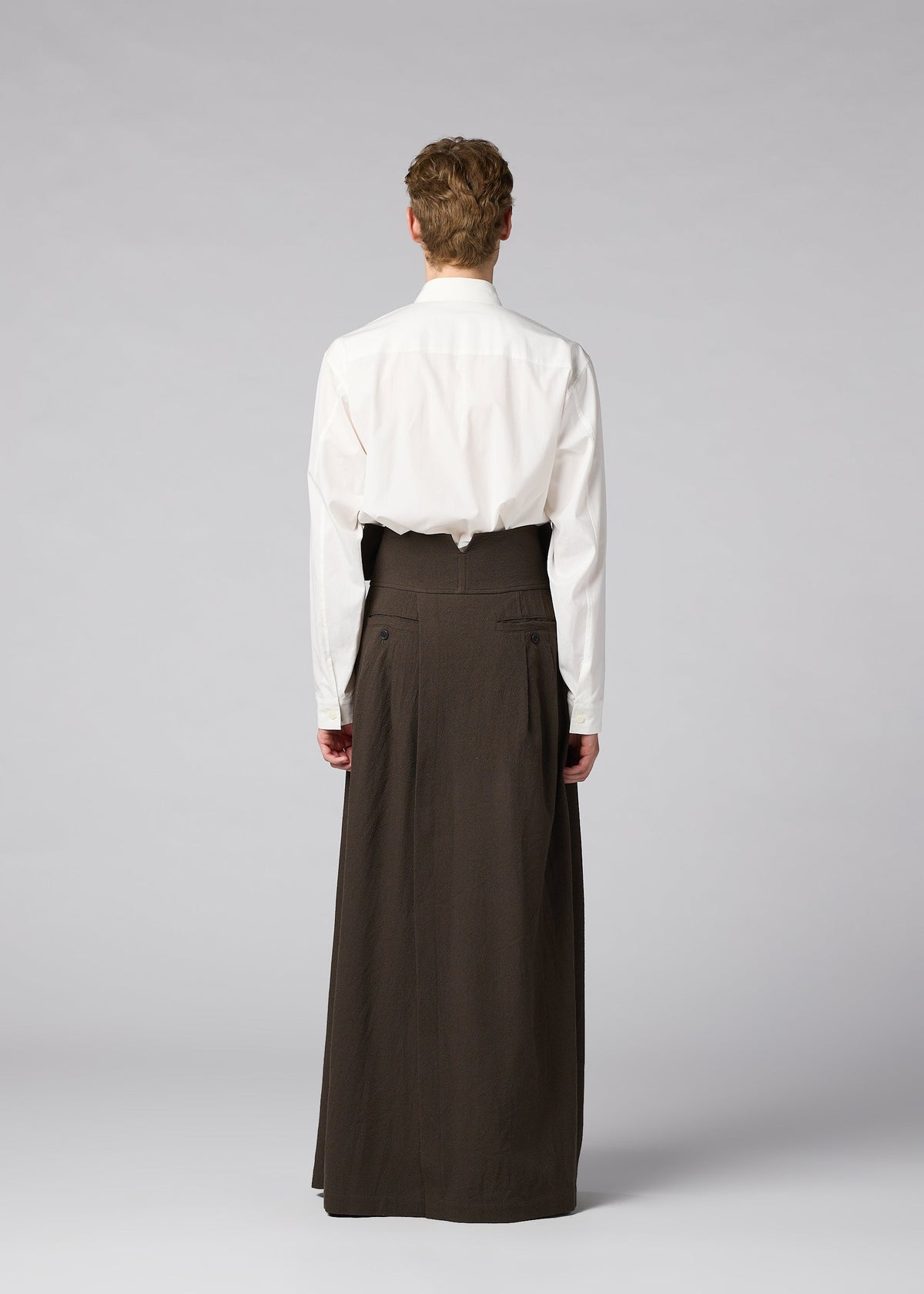 Zoomed view A person stands facing away in a white shirt and IM MEN SHRINK WOOL wide hard-twist wool pants, set against a plain light gray background.