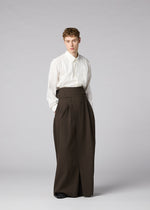 A person stands against a plain backdrop, wearing a white long-sleeve shirt and IM MEN’s SHRINK WOOL high-waisted, hard-twist wool wide pants for a minimal, modern look.