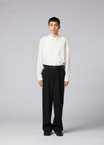 A person stands facing forward, wearing IM MEN’s FRONT BACK white button-up shirt tucked into loose matte wool trousers with a belt, paired with black shoes, against a plain light gray background.