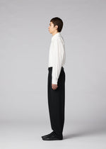A person stands in profile against a plain gray background, wearing a white dress shirt, IM MEN’s FRONT BACK men’s autumn winter pants in classic black, and coordinating black shoes.