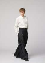 A person in a white dress shirt, tucked into IM MEN GRADATION WOOL pants with hands in pockets, stands against a plain light background.