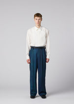 A person with short hair faces forward, wearing a white long-sleeve shirt tucked into high-waisted, loose GRADATION WOOL pants from IM MEN. The background is plain light gray.