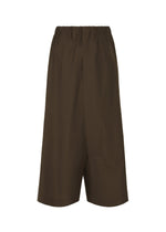 The SUAVE shorts by IM MEN are brown, knee-length with a relaxed silhouette and elastic waistband. They have a loose fit like sarouel pants, feature no visible patterns or embellishments, and are displayed against a white background.